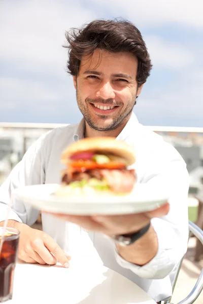 Genç adam bir hamburger yeme — Stok fotoğraf