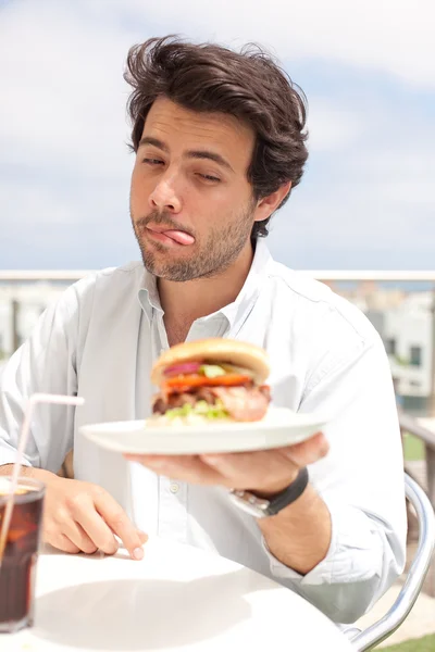 Jovem comendo um hambúrguer — Fotografia de Stock