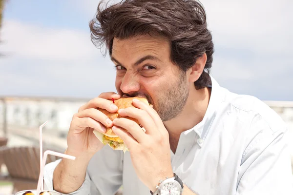 Jovem comendo um hambúrguer — Fotografia de Stock