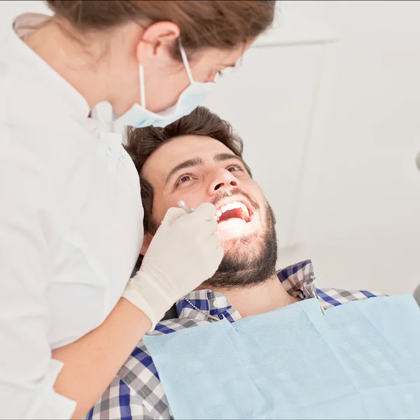Χαρούμενος νεαρός και μιας γυναίκας σε μια οδοντική εξέταση σε οδοντίατρο — Φωτογραφία Αρχείου