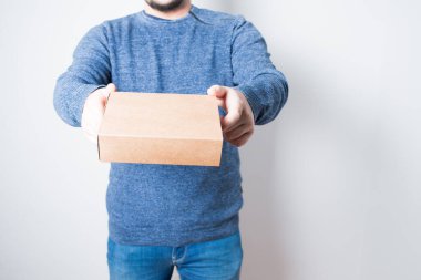 Kot pantolon ve kazakla karton kutu getiren isimsiz bir yetişkin. Beyaz arkaplan