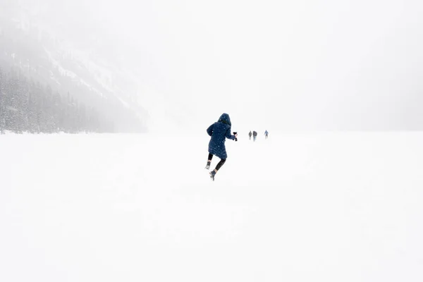 Young person jumping in the air in a winter landscape with snow. Frozen Lake Louise, Banff National Park, Alberta, Canada