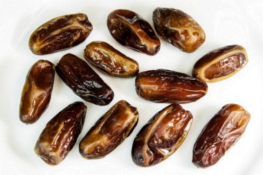Randevular. Beyaz arka planda kurumuş tarihler. Lezzetli, kahverengi hurmalar. Kurumuş meyve