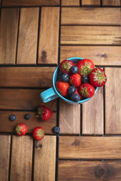 Çilek ve mavi bir bardak yaban mersini