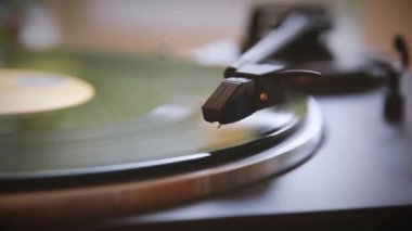 El, vinil plak açar. İğne vinil plaktan yükseliyor. Vinil plak dönüyor. İğne vinil plakla çalınıyor. Eski pikap. Eski.