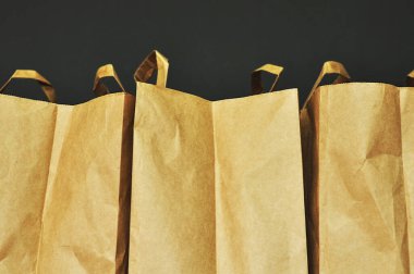 Sürdürülebilir kağıt alışveriş torbaları. Boş kahverengi çantalar, koyu arka planda izole edilmiş. Metin için boş alan. Market konsepti, yemek teslimatı, ulaşım çözümleri