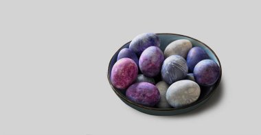 Kasede renkli yumurtalar. Çilekli yumurta boyası. Kırılganlık, yemek sanatı, Paskalya konsepti. Tek renkli arka planda izole edilmiş. Gerçekçi yatay görüntü. Mavimsi, mor palet