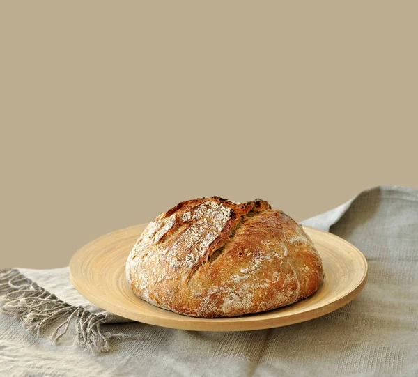 Yuvarlak ekşi ekmek, çıtır çıtır ekmek, un tozuyla kaplanmış, ahşap bir yüzeyde kırsal keten kumaş üzerinde dinleniyor. Ev yapımı fırın, geleneksel pişirme konsepti. Gerçekçi görüntü, Negatif boşluk