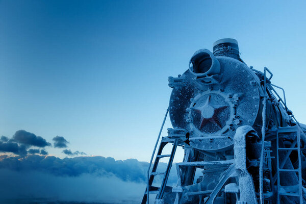 Front of old steam locomotive in winter covered with hoarfrost