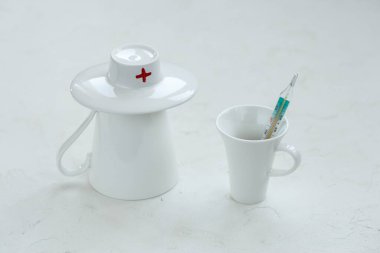 İki beyaz bardak - biri doktor olarak, diğeri termometresi olan bir hasta olarak.