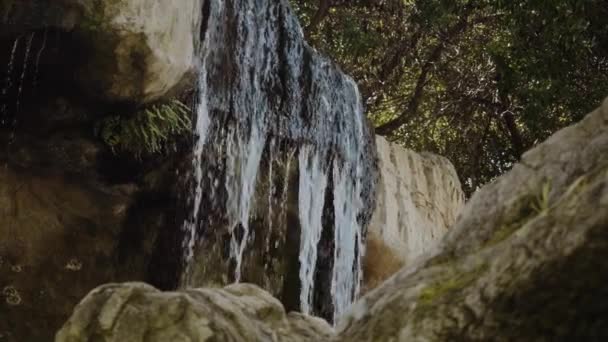 Een kleine waterval in de schaduw, vlakbij de rotsen. Close-up opname. — Stockvideo