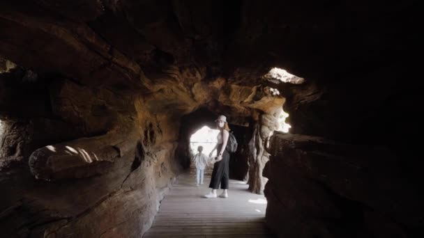 Mother and daughter are walking in a tunnel made of stone. — Stockvideo