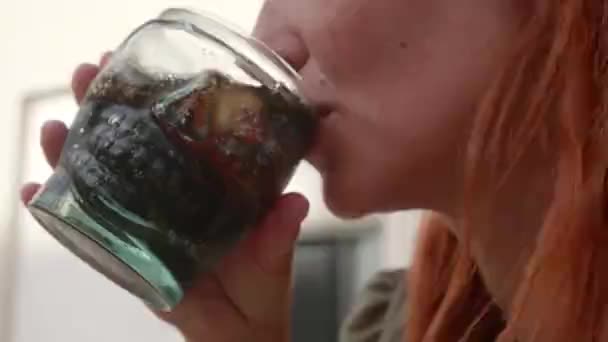 Το κορίτσι πίνει λεμονάδα από ένα ποτήρι με τη μορφή κρανίου. κοντινό πλάνο. — Αρχείο Βίντεο