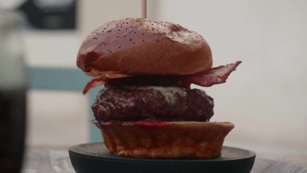 Zbliżenie pysznego burgera z serem i bekonem. Restauracja w tle — Wideo stockowe