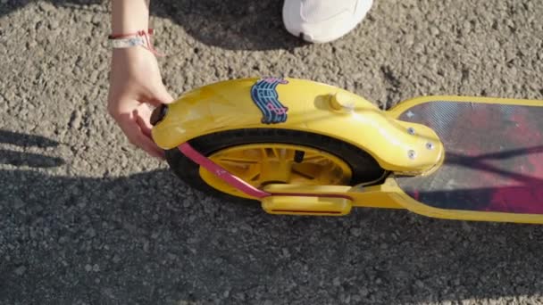 A young woman checks the wheel of the electro scooter on the street. Top view — Stock Video