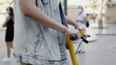 Bir kadın şehirde scooter 'a biniyor. Elektrikli scooter ile gidip gelmek