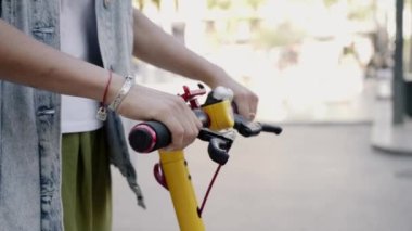 Bir kadın şehirde scooter 'a biniyor. Elektrikli scooter ile gidip gelmek