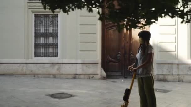 Una mujer está montando un scooter por la ciudad. Viajes en scooter eléctrico — Vídeos de Stock