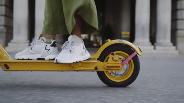 Женские ноги на электрическом скутере разъезжают по городу. — стоковое видео