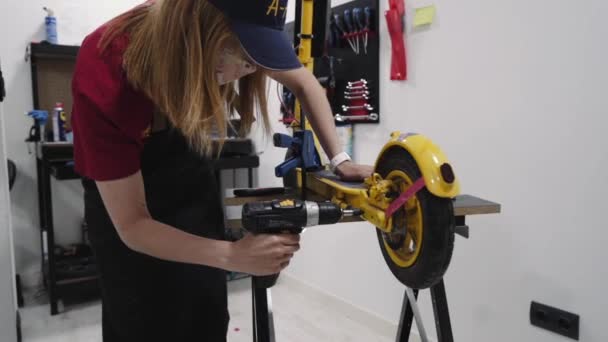 Молода красива жінка-механік працює в ремонтному магазині, фіксуючи скутер . — стокове відео