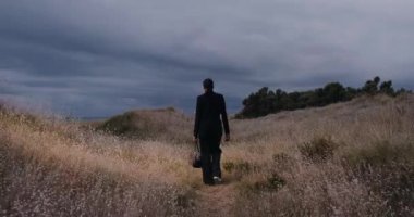 Plajda çantası olan siyah seksi bir kız, geceleri sahada yürüyor, geniş açılı.