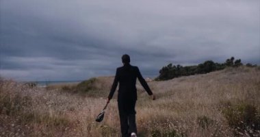 Plajda çantası olan siyah seksi bir kız, geceleri sahada yürüyor. Geniş açı