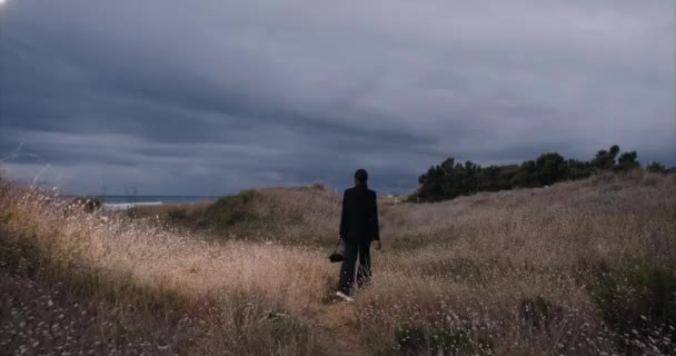 Menina sexy preta com um saco na praia, caminha no campo à noite, tiro largo — Vídeo de Stock
