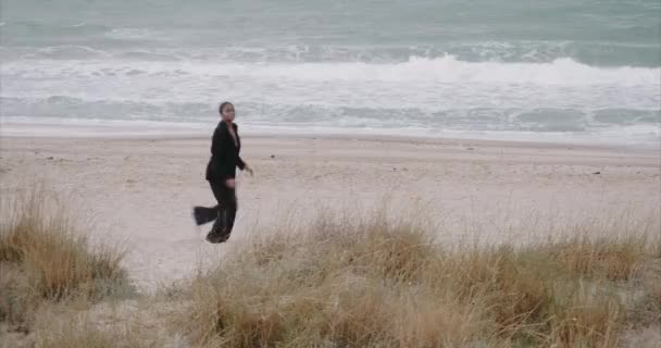 A black sexy girl in a jacket runs along the beach. Sunrise. — Stock Video