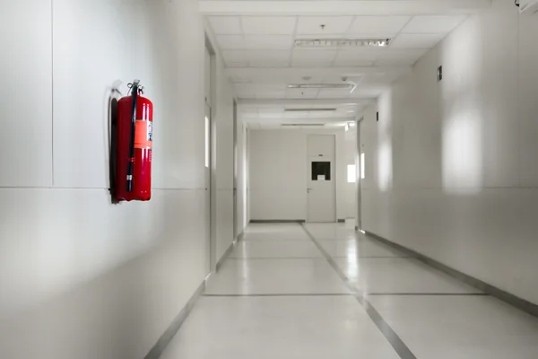 Fire extinguisher in empty corridor — Stock Photo, Image