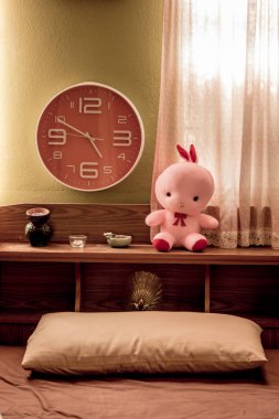 Yatak odasındaki yatak başlığı bir saat ve bir bebekten oluşuyor..