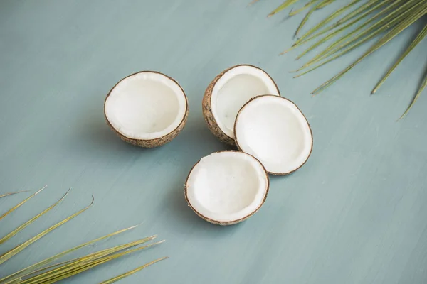 Vier Kokosnusshälften Und Die Blätter Der Kokosnuss Lagen Auf Türkisfarbenem — Stockfoto