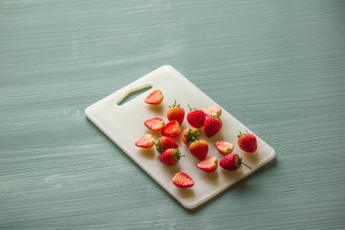 Çilekler ikiye bölünmüş ve kesme tahtasına birkaç rakam yazmışlar..