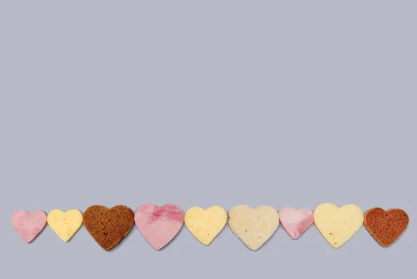 sliced bread, sausage and cheese, heart-shaped pieces on a gray background, Valentine\'s Day fast food concept, horizontal image with soft focus and place for text