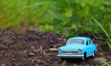 Mavi eski model oyuncak araba yerde duruyor.