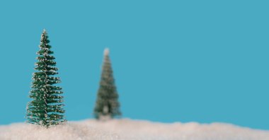 Mavi zemin üzerinde küçük yeşil Noel ağaçları, yeni yıl minimalizmi kavramı.