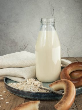  Alternatif sütlü vejetaryen ayakkabılı süt. Hafif arka planda yulaf ezmesi ve yulaf sütü. Gri arka planda yulaf sütü. Sağlıklı alternatif süt, çay kaşığında yulaf ezmesi ve mavi tabakta borazan, ip peçete ve gri arka plan. .