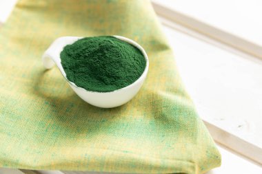 Sarı peçetedeki yeşil spirulina tozu. Sarı arka planda organik yeşil spirulina tozu. Süper yiyecekler. Vitamin proteini ve beta karoten takviyesi. Dokunulmazlık desteği . 