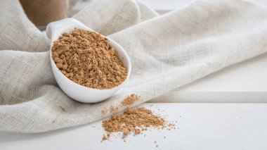 Beyaz tahta bir masada beyaz bir kasede Guarana tozu. Süper yiyecekler. Enerji içeceği .