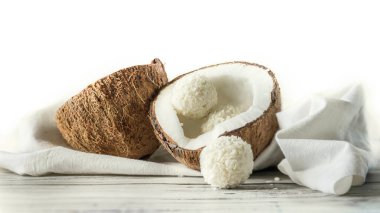 Tahta bir masada iki yarım hindistan cevizi ve hindistan cevizi şekeri. Beyaz peçetede hindistan cevizi. Kopya alanı olan el yapımı hindistan cevizi tatlısı. Bir hindistan cevizi ile yatay yönelim resmi .