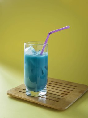 Iced blue matcha latte drink concept . Batterfly pea tea  drink on a yellow background . Summer drink .  Trendy drink . Superfoods .