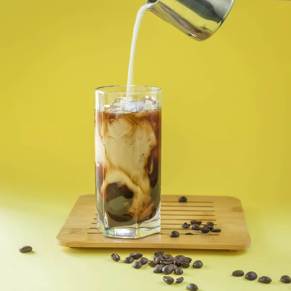 Pouring Milk Glass Iced Coffee Yellow Background Iced Coffee Concept — Stock Photo, Image