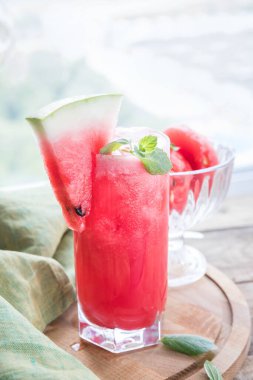 Bardakta karpuz, tahta kesme tahtasının üzerinde yeşil peçete..   