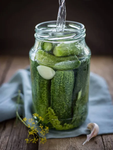 Pickles .Pouring brine into cucumbers .  Gucumbers , garlic ,dill, currant leaves in a glass jar. Russian Traditional food .  Pickled cucumbers . Recipes .