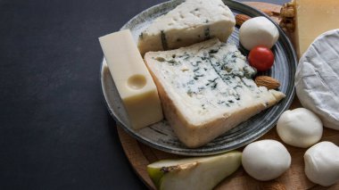 Siyah arka planda, fotokopi alanı olan bir peynir tahtası. Karışık peynir. Parmesan, camembert, brie, mozzarella ve Masdam siyah arka plan manzaralı. Peynir dükkanı. Peynir menüsü .