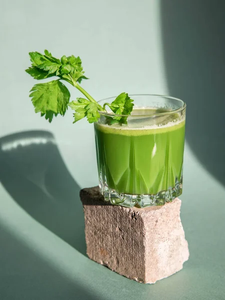 Celery juice concept.  Celery juice  in a glass and celery  on a light background.
