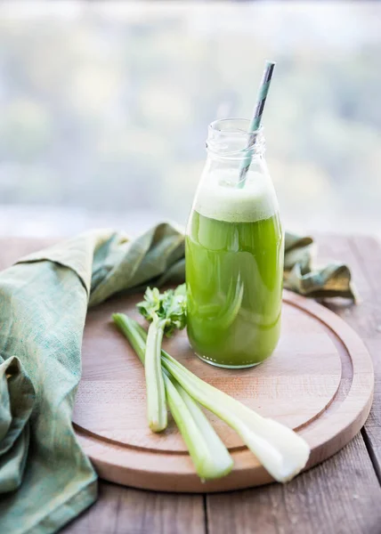 Celery juice.  Celery juice  in a glass bottle  and celery  on a wooden background.