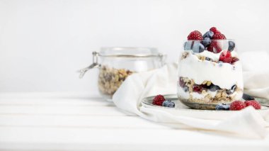 Meyveli granola parfe ve fotokopi alanı ile yoğurt. Granola, ahududu ve yaban mersinli parfe beyaz arka planda fotokopi alanı. Bardakta granola. . 