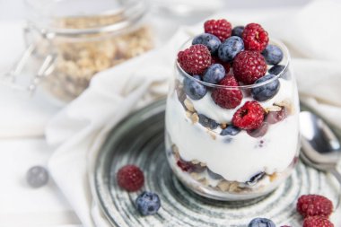 Meyveli granola parfe ve fotokopi alanı ile yoğurt. Granola, ahududu ve yaban mersinli parfe beyaz arka planda fotokopi alanı. Bardakta granola. . 