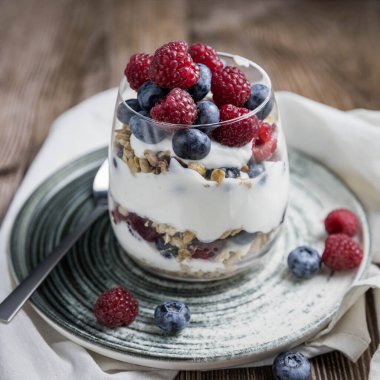 Böğürtlenli ve yoğurtlu granola parfe. Siyah arka planda granola, ahududu ve yaban mersinli parfe. Bardakta granola. . 