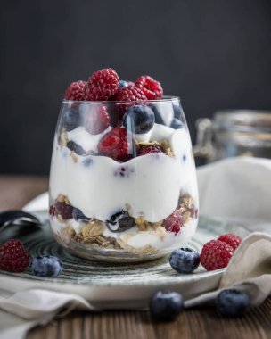 Böğürtlenli ve yoğurtlu granola parfe. Siyah arka planda granola, ahududu ve yaban mersinli parfe. Bardakta granola. . 